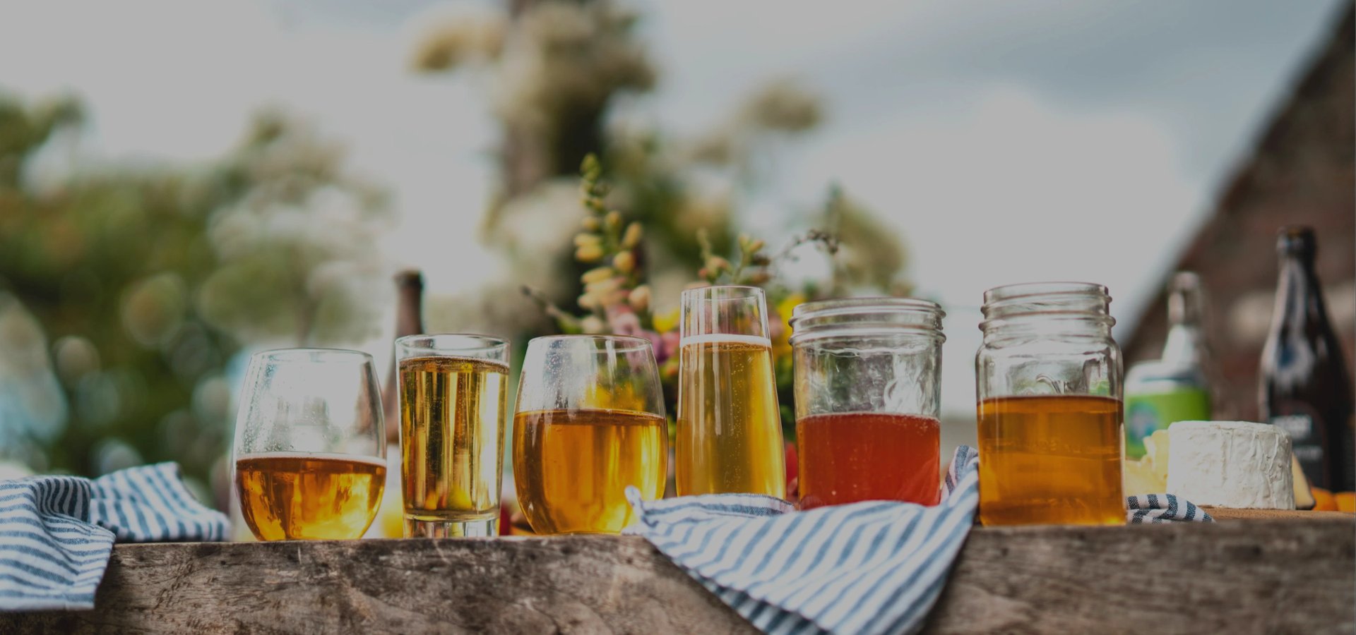 glasses and mason jars of wine on a thick wood table